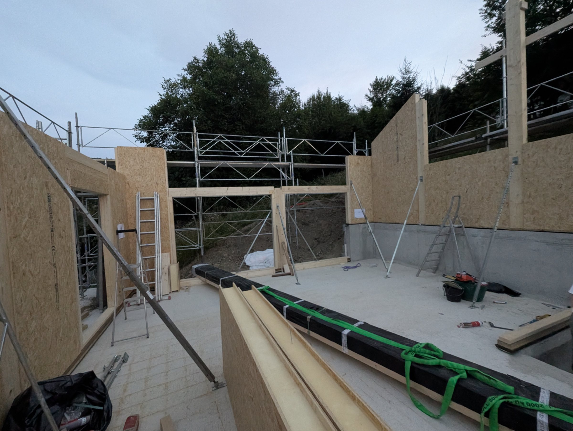SIP panel construction: panel walls faced with OSB board going up on the concrete base