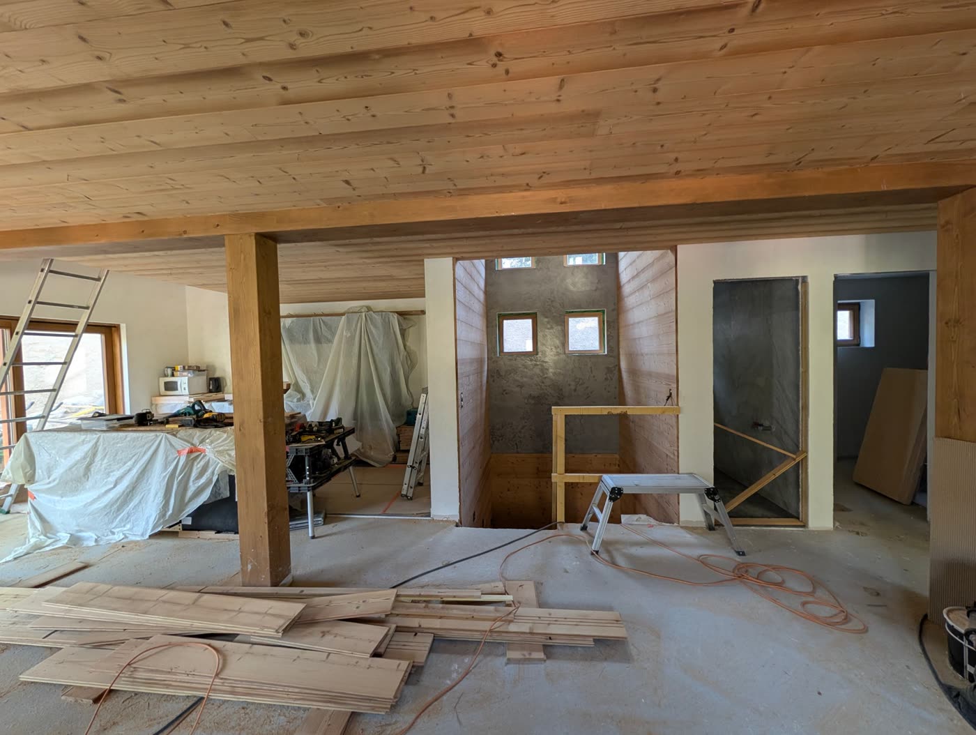 Main living floor under construction, with timber beams, stairwell and bathroom doorways