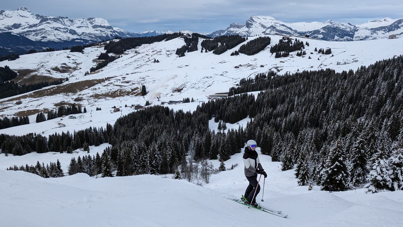 A skier on a snowy piste above Saint-Gervais with the Mont Blanc massif behind